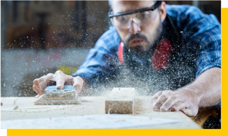 carpenter blowing sawdust off workbench