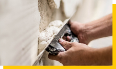 hands applying plaster to hole in wall