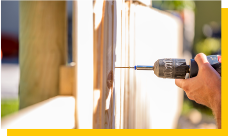 hand using drillldriver to erect fence